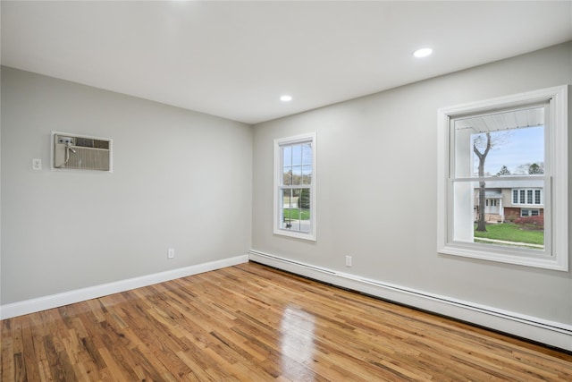 spare room featuring a wall mounted air conditioner, recessed lighting, baseboards, wood finished floors, and a baseboard heating unit