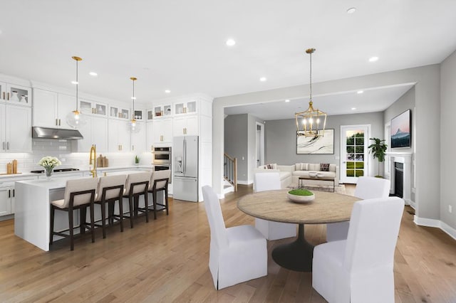 dining room with a chandelier, stairway, light wood-style flooring, and recessed lighting