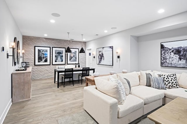 living room with baseboards, an accent wall, light wood-type flooring, and recessed lighting
