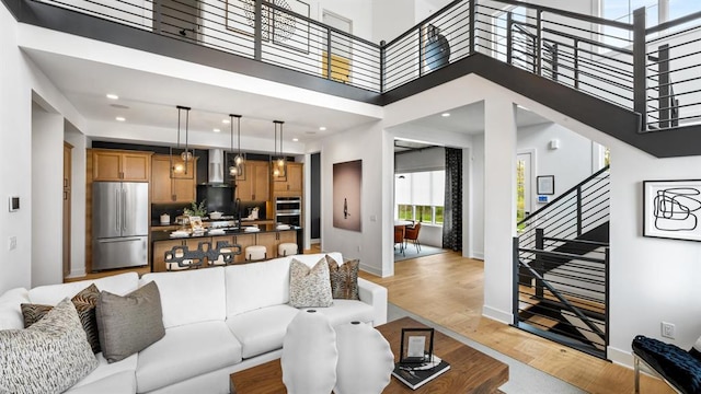 living room with a high ceiling, stairs, baseboards, and light wood-type flooring