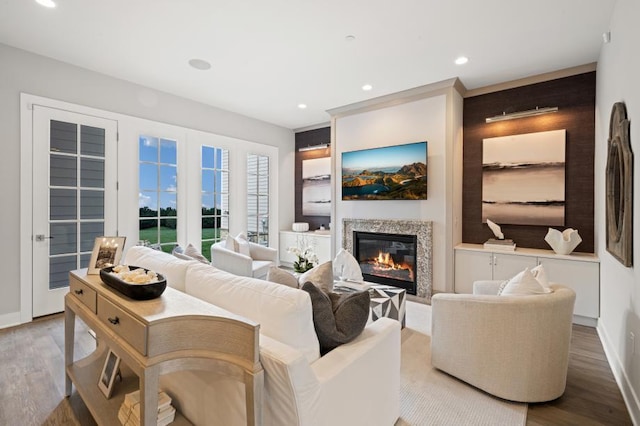 living area with baseboards, recessed lighting, wood finished floors, and a glass covered fireplace