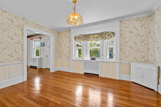 interior space featuring hardwood / wood-style flooring, plenty of natural light, radiator, and a wainscoted wall