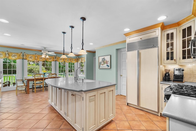 kitchen with crown molding, a ceiling fan, paneled refrigerator, cream cabinetry, and a sink