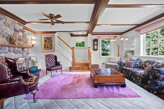 living area with a ceiling fan, a stone fireplace, crown molding, wood finished floors, and stairway