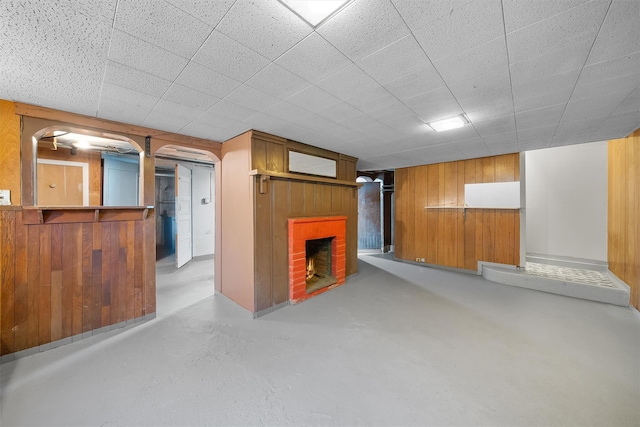 unfurnished living room with finished concrete floors, wooden walls, and a fireplace