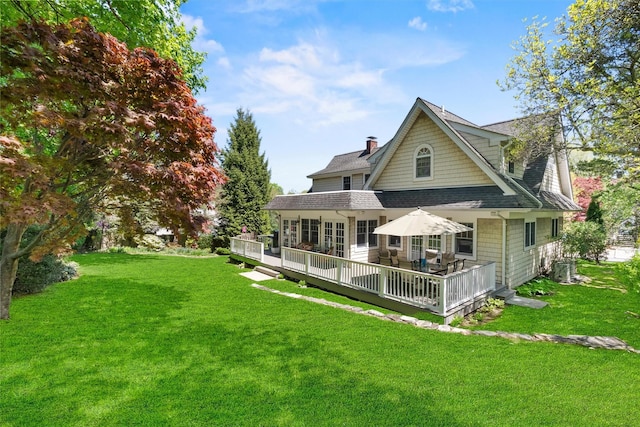 back of house featuring roof with shingles, central air condition unit, a wooden deck, a chimney, and a lawn