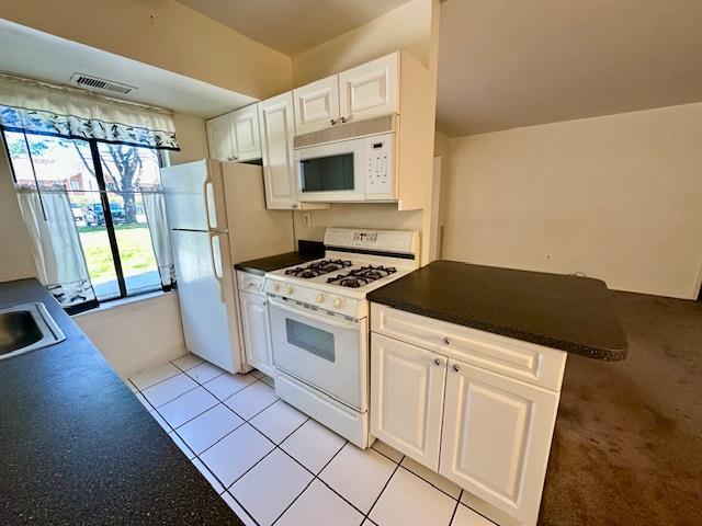 3 Kiowa Ct Unit 3K, Coram, NY 11727 - kitchen featuring white cabinets, a peninsula, dark countertops, visible vents, and white appliances