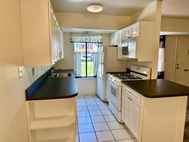 3 Kiowa Ct Unit 3K, Coram, NY 11727 - kitchen with white cabinets, dark countertops, white gas stove, and a sink
