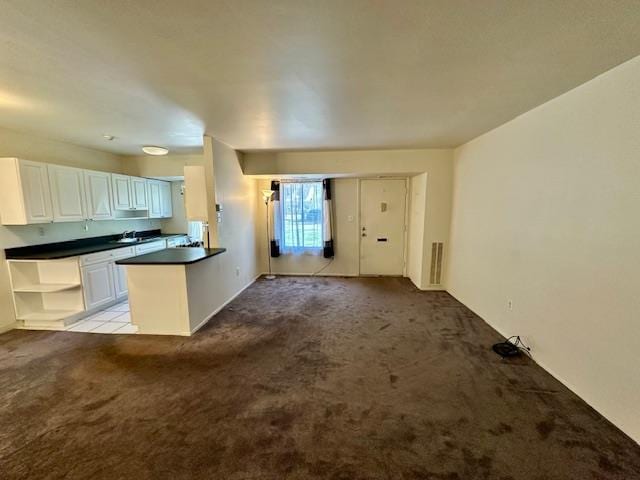 3 Kiowa Ct Unit 3K, Coram, NY 11727 - kitchen featuring dark countertops, open shelves, light colored carpet, white cabinets, and a peninsula