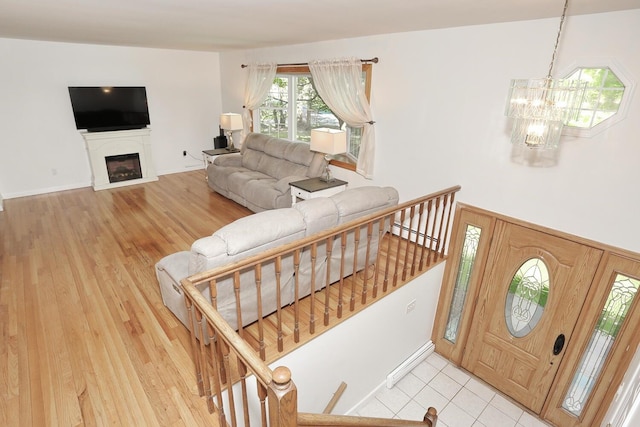 foyer featuring a chandelier, a fireplace, light wood finished floors, and a baseboard heating unit