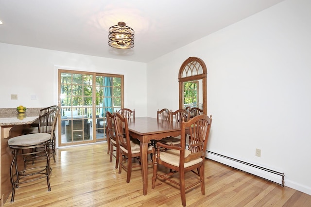 dining space with baseboard heating, light wood-type flooring, and a chandelier