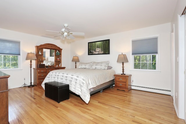 bedroom with a baseboard radiator, light wood-type flooring, and a ceiling fan