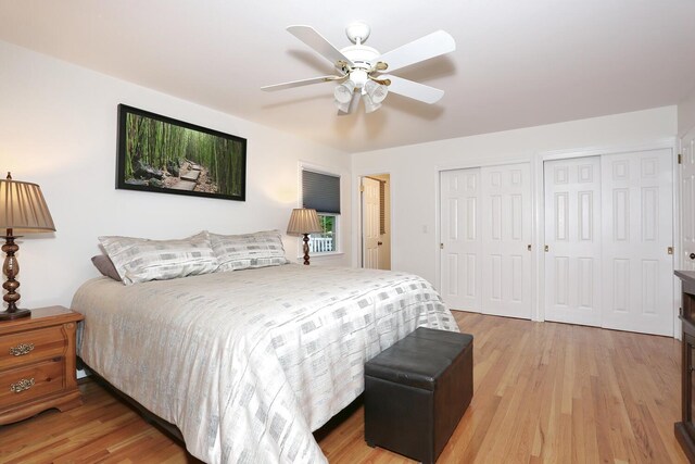 bedroom featuring two closets, light wood-style floors, and ceiling fan