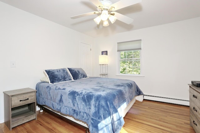 bedroom featuring a baseboard radiator, wood finished floors, and a ceiling fan