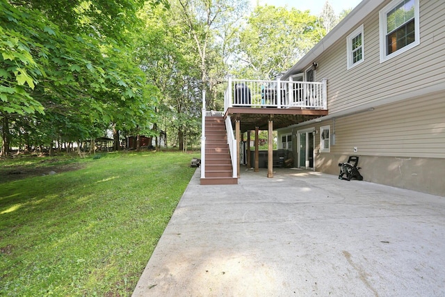 view of green lawn featuring stairway, a wooden deck, concrete driveway, and a patio area