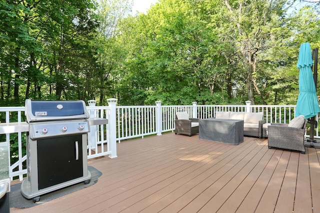 deck featuring outdoor lounge area, area for grilling, and view of wooded area