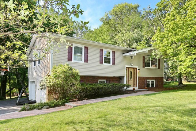raised ranch featuring a garage, a front lawn, and driveway