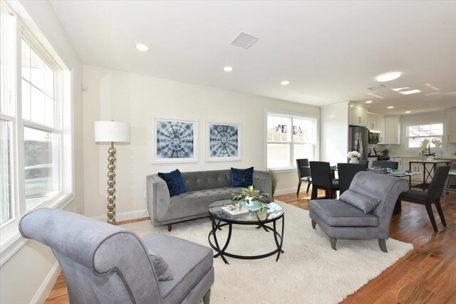 living area with visible vents, light wood-style flooring, and baseboards