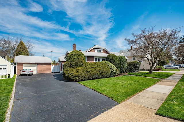 view of front of home with a chimney, a front lawn, a detached garage, and an outdoor structure