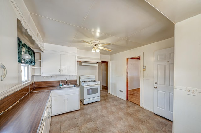 kitchen featuring open shelves, a sink, white gas range, and white cabinetry