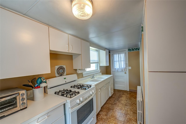 kitchen with radiator heating unit, a sink, a toaster, white gas range oven, and light countertops