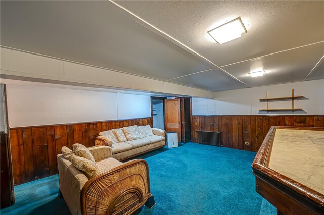 living area featuring carpet floors, a textured ceiling, wood walls, and a wainscoted wall