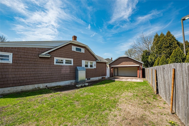 rear view of house featuring fence, a lawn, an outdoor structure, and a garage