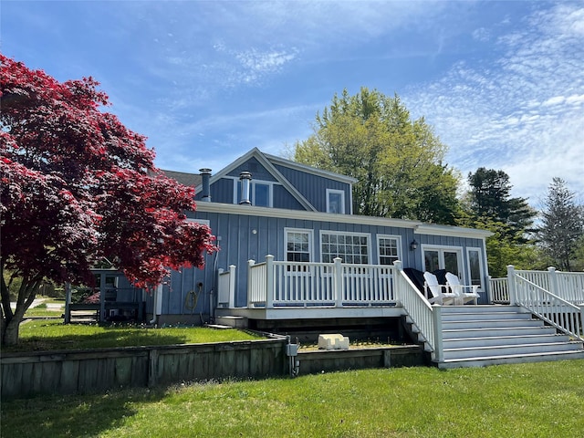 rear view of house featuring a lawn, a wooden deck, stairway, and board and batten siding