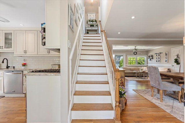 stairs featuring wood finished floors, recessed lighting, and ornamental molding