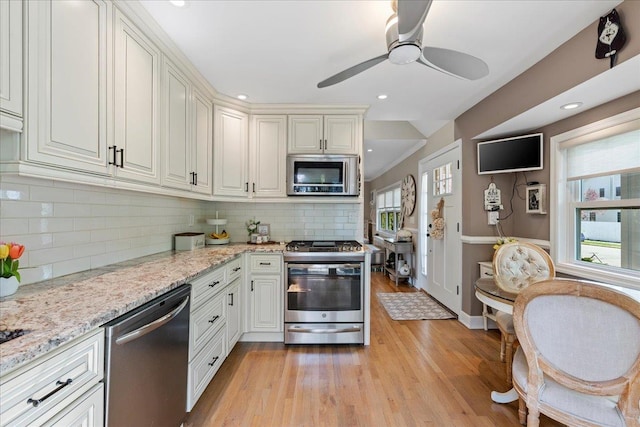 kitchen with stainless steel appliances, light wood-style floors, decorative backsplash, ceiling fan, and light stone countertops