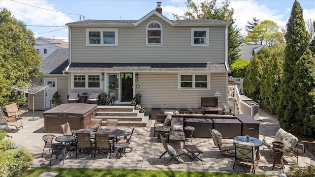 rear view of house with outdoor lounge area, a patio area, a hot tub, and a shingled roof