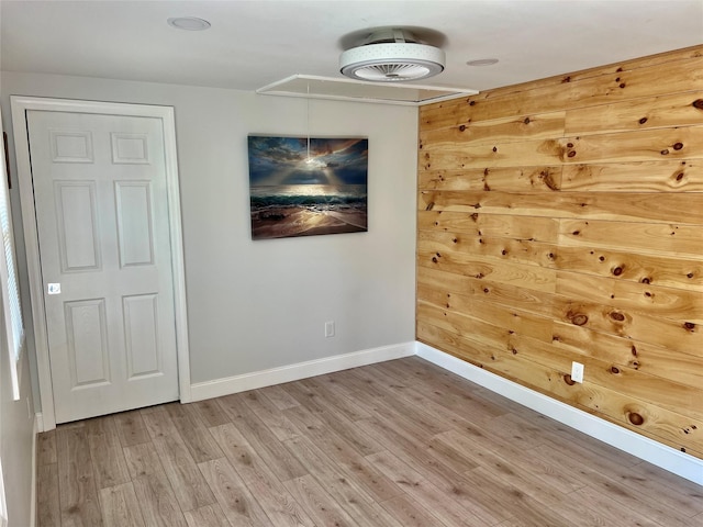 empty room with attic access, light wood-type flooring, and baseboards