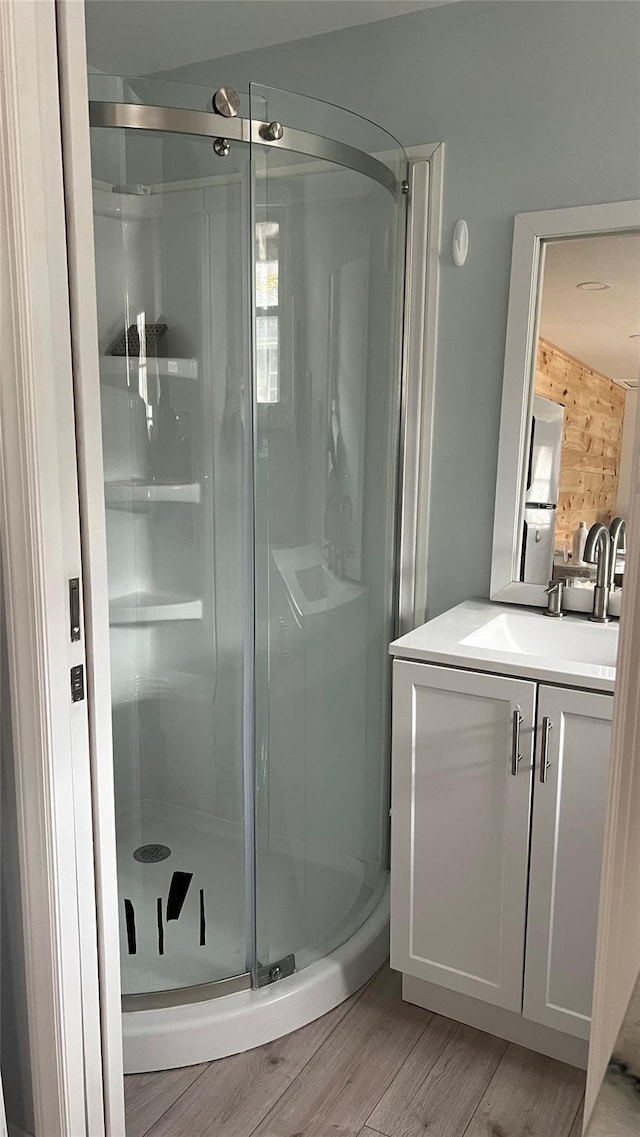 full bath with vanity, wood finished floors, and a shower stall