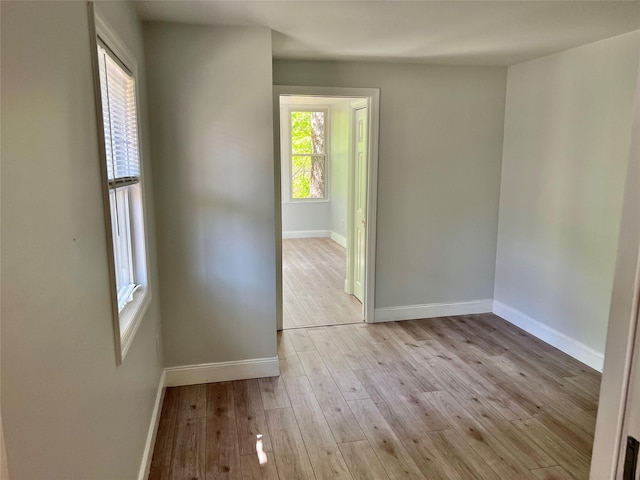 unfurnished room featuring baseboards and light wood-style floors
