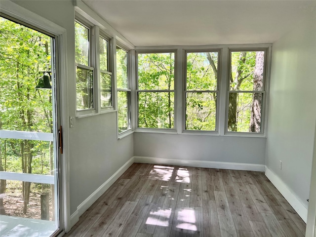unfurnished sunroom with hardwood / wood-style flooring and baseboards
