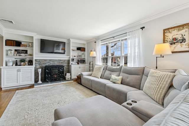 living area with ornamental molding, visible vents, wood finished floors, and a fireplace