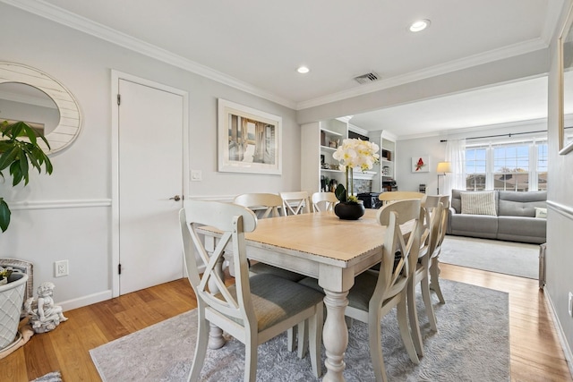 dining area featuring light wood finished floors, recessed lighting, crown molding, visible vents, and baseboards