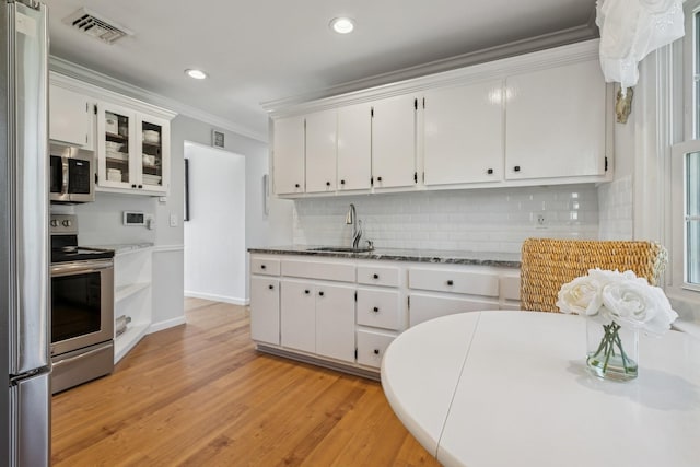 kitchen featuring a sink, stainless steel appliances, visible vents, ornamental molding, and white cabinets