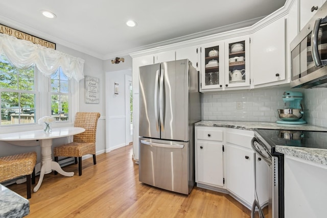 kitchen featuring stainless steel appliances, light wood-style floors, tasteful backsplash, ornamental molding, and white cabinets