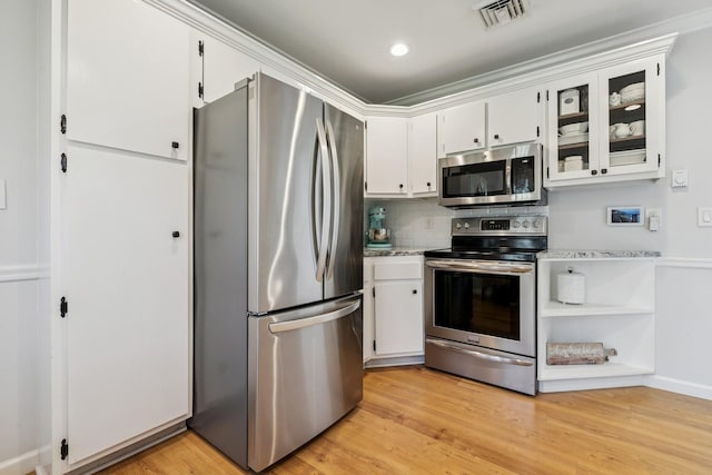 kitchen with stainless steel appliances, light wood-style floors, light countertops, white cabinetry, and visible vents