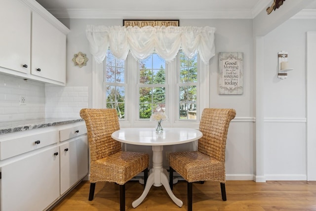 dining room with baseboards, light wood-type flooring, and ornamental molding