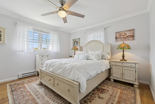 bedroom featuring baseboard heating, ornamental molding, wood finished floors, and multiple windows