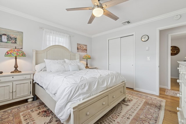 bedroom featuring visible vents, light wood-style floors, a closet, ornamental molding, and a ceiling fan