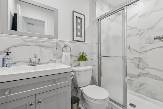 bathroom featuring toilet, tile walls, a shower stall, and vanity