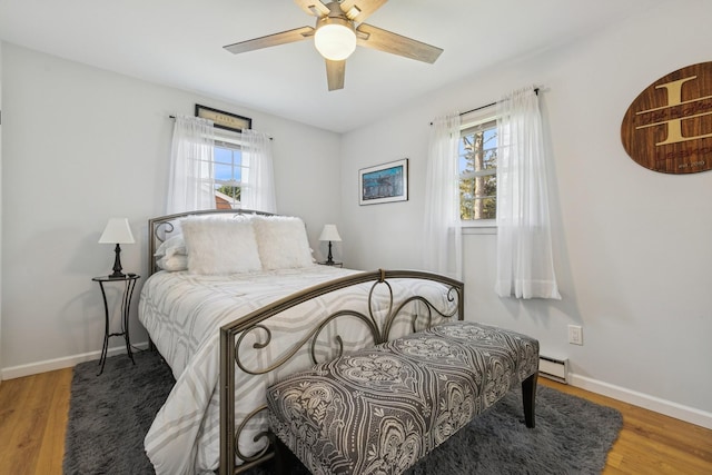 bedroom with baseboards, wood finished floors, a ceiling fan, and a baseboard radiator