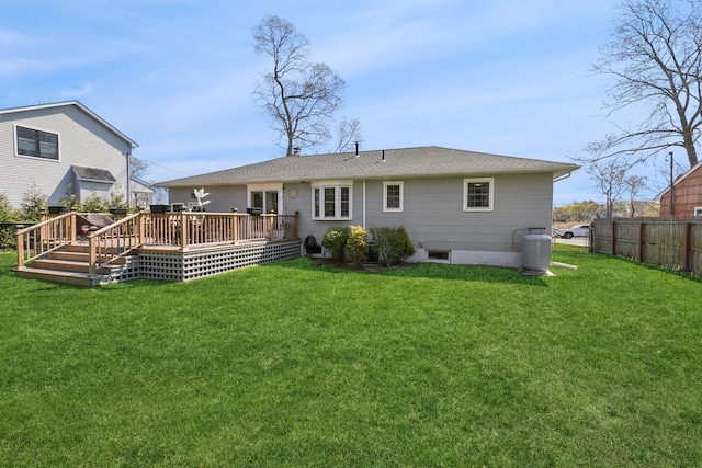 rear view of property with fence, a yard, and a wooden deck