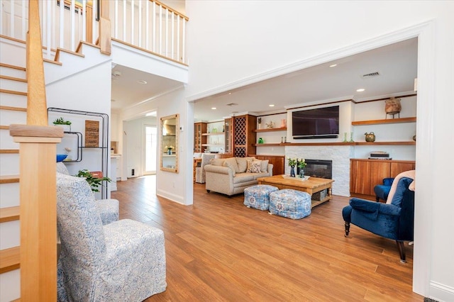 living room with stairway, a fireplace, visible vents, baseboards, and wood finished floors