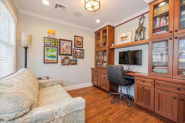 office area featuring crown molding, visible vents, baseboards, built in study area, and dark wood-style flooring