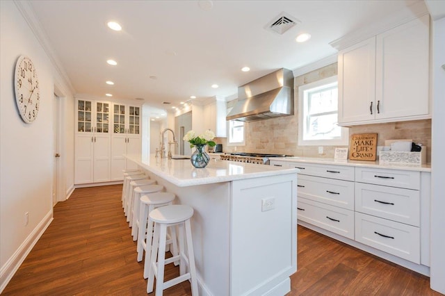 kitchen featuring white cabinets, backsplash, wall chimney range hood, and a sink