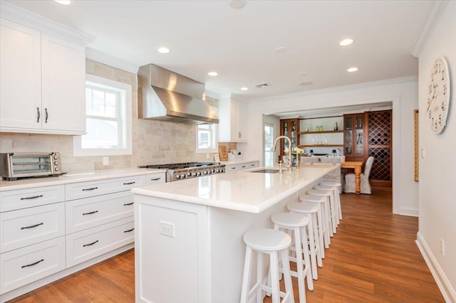kitchen with a sink, tasteful backsplash, crown molding, wall chimney range hood, and a toaster